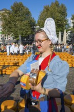 Woman in traditional traditional costume selling pieces of cheese at a market in sunny weather,