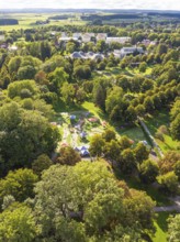 View of a wooded area with embedded park and buildings in the background under a slightly cloudy