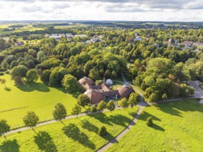 Extensive green landscape with shade, surrounded by a variety of trees and a central building, Bad