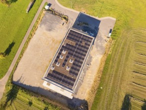 Top view of solar roof of a building with surrounding fields and car park, new building with green