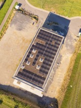 Top view of building with solar roof surrounded by an open area and fields, new building with green