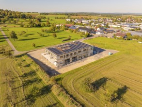 New building with solar panels, embedded in green fields, near a village, new building with green