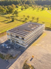 Building with solar panels and scaffolding in a landscaped setting, new build with green roof and