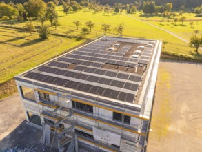 Building with solar panels and scaffolding in a green landscape, new building with green roof and