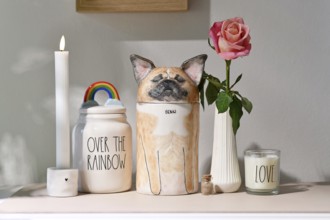 Germany - August 30th 2025: Custom pet dog urn shaped like a French Bulldog surrounded by candle