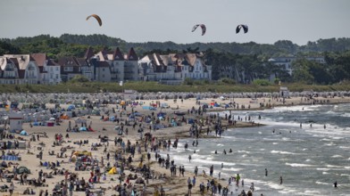 Kitesurfers float along a lively beach, surf, Warnemünde, Rostock, Mecklenburg-Vorpommern, Germany