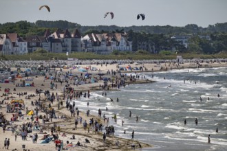 Lively beach with holidaymakers in the sea and on the beach, kite surfers in the surf, Warnemünde,