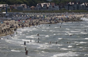 Holidaymakers on the beach and in the sea, waves, beach chairs in the background, Warnemünde,