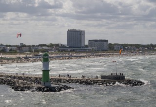 Green and white lighthouse, pier light Westmole in front of lively beach and hotels in the