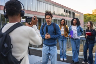 Young man with a microphone speaking while being filmed by another student wearing headphones, with