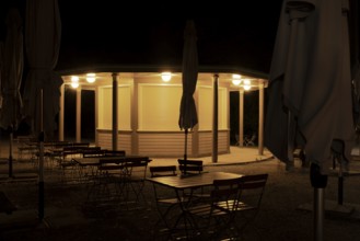 Night shot of a closed kiosk with seating and folded sunshades in the Herrenhausen Gardens,