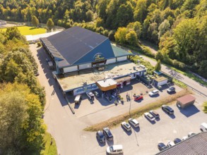 Building with large car park, surrounded by forest and green areas, sunny atmosphere, Polarion Ice
