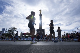 Runners run around the Victory Column against the backlight of the sun on the Great Star at the