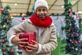 Happy young man holding colorful christmas gifts while enjoying the festive atmosphere of a