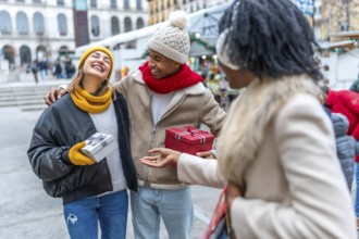 Happy multi ethnic friends joyfully exchanging christmas gifts while enjoying the festive