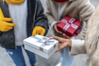 Friends exchanging christmas gifts while enjoying a winter day out in the city, celebrating the joy