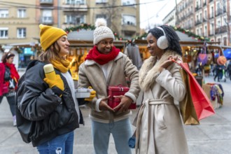 Happy multi ethnic friends exchanging christmas gifts while enjoying a stroll through a winter