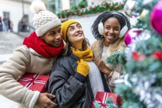 Happy multi ethnic friends holding christmas gifts and enjoying christmas time together outdoors