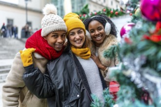 Happy multi ethnic friends enjoying christmas city during winter holidays, wearing winter clothes
