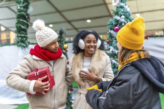 Happy friends exchanging gifts and enjoying christmas time together at a decorated christmas market