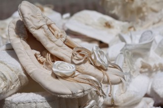 Satin ballet shoes with floral embellishment, embedded in a soft, romantic atmosphere, weekly