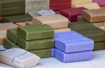 Colourful soap bars in different colours carefully stacked, weekly market market, Tuscany, Italy