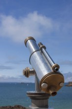 Binoculars point to the vast blue sea under a clear sunny sky, Saint Malo, Brittany, France