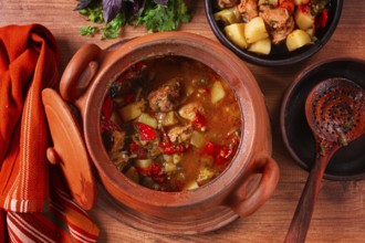 Chanakhi, a Georgian dish. in a clay pot, on a wooden table, stewed meat with vegetables, homemade,