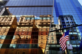 Reflection in the glass facade and with the flag of the USA, New York City, USA