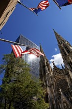 Towers of St Patrick's Cathedral in front of skyscrapers, waving US flags, New York City, USA
