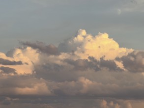 Mystical impression of cumulus cluster clouds at dusk illuminated by warm light, in the background