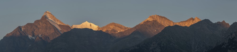 The mountain peaks glow with a soft orange light as the sun sets, creating a spectacular panorama.