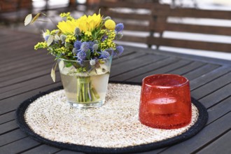 Close up of yellow and purple flower bouquet and storm lamp with candle decoration on table