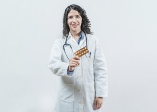 Female doctor holding pills tablet isolated. Portrait of a young female doctor showing pills tablet