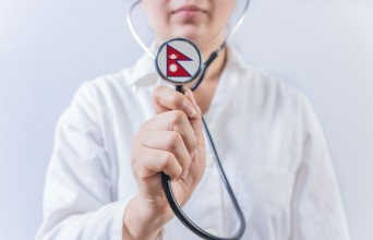 Female doctor holding stethoscope with Nepal flag. National health system of Nepal