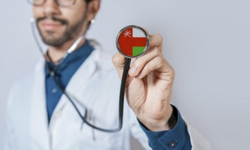 Doctor holding stethoscope with Oman flag. Oman health and care concept, Oman flag on stethoscope