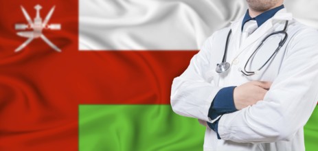 Oman healthcare concept. Male doctor on Oman flag. Doctor with crossed arms on Oman flag