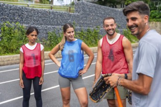Four happy baseball players are standing together on the field after a game, chatting, smiling, and