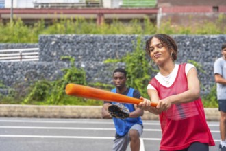 Young woman with red training shirt holding a baseball bat ready to hit the ball during a match