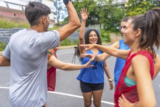 Group of happy basketball players in sportswear celebrating victory, giving high five to each other