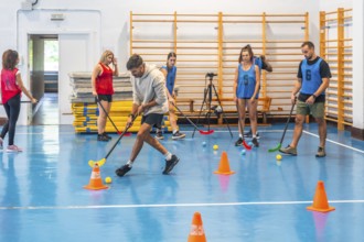Group of athletes practicing floorball, passing the ball with sticks and maneuvering around cones