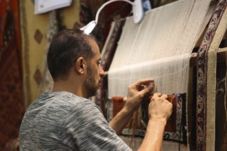 A Syrian weaver showcases the craft of traditional textile-making inside the Damascus International