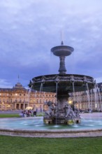 Evening atmosphere at Schlossplatz Stuttgart. View of the New Palace. Illuminated fountain bowl at