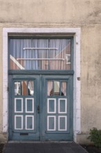 Blue wooden door with windows and white curtains on a rustic building, Old Town Burgsteinfurt,