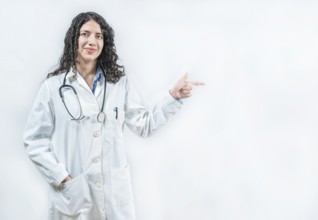 Smiling female doctor pointing at an advertisement to the side isolated. Young female doctor
