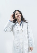 Doctor with hand on ear listening to a rumor, isolated. Latin female doctor hearing a rumor,