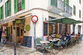 Food restaurant with people sitting at tables by a street in the old town of Palma, Palma de