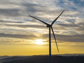 A single wind turbine stands majestically against a breathtaking sky at sunrise, near Schorndorf,