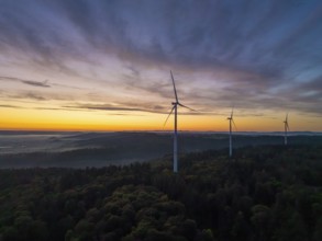 Three wind turbines on a green hill at sunrise with sweeping mountain views, near Schorndorf,
