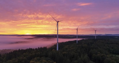 Wind turbines above a forest in front of sunrise with dramatic cloud formation, near Schorndorf,